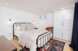 This cozy bedroom features a stylish black metal bed frame, complemented by a neutral color palette and hardwood floors.