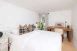 This inviting bedroom boasts a serene atmosphere with its bright white walls and natural light.