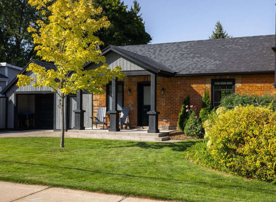 Charming brick home with a welcoming front porch and lush landscaping.