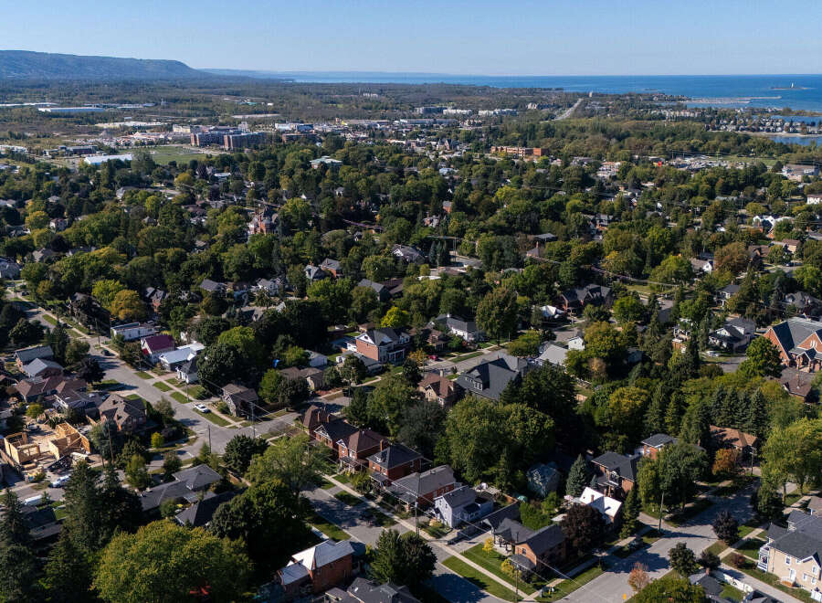 An aerial view showcases a charming residential area, highlighting the lush greenery and well-maintained homes.