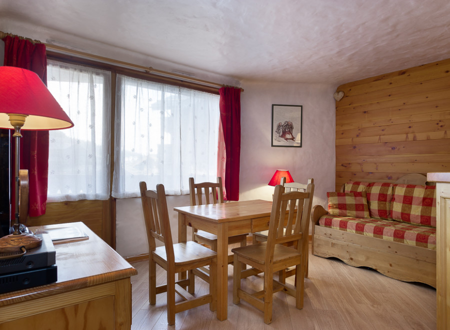 Cozy chalet apartment featuring a wooden interior, comfortable sofa bed, and dining area.