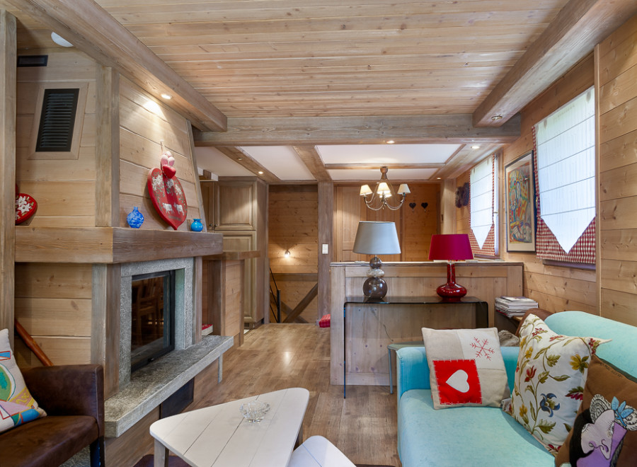 Cozy chalet living room with wood-burning fireplace, exposed wooden beams, and comfortable seating.