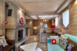Cozy chalet living room with wood-burning fireplace, exposed wooden beams, and comfortable seating.