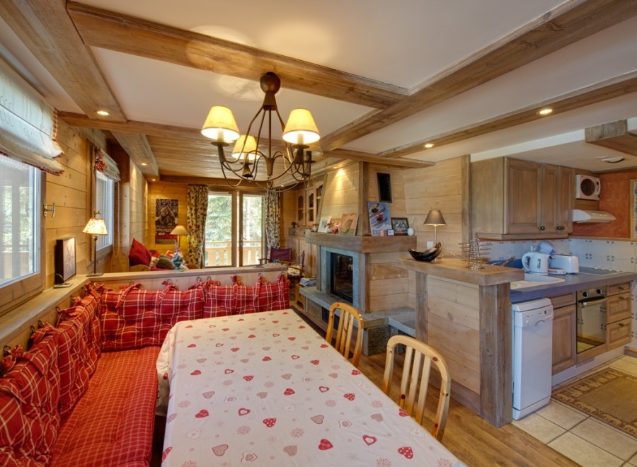 Cozy chalet apartment with a charming wooden interior, featuring a built-in banquette seating area and a dining table with a festive tablecloth.