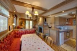 Cozy chalet apartment with a charming wooden interior, featuring a built-in banquette seating area and a dining table with a festive tablecloth.