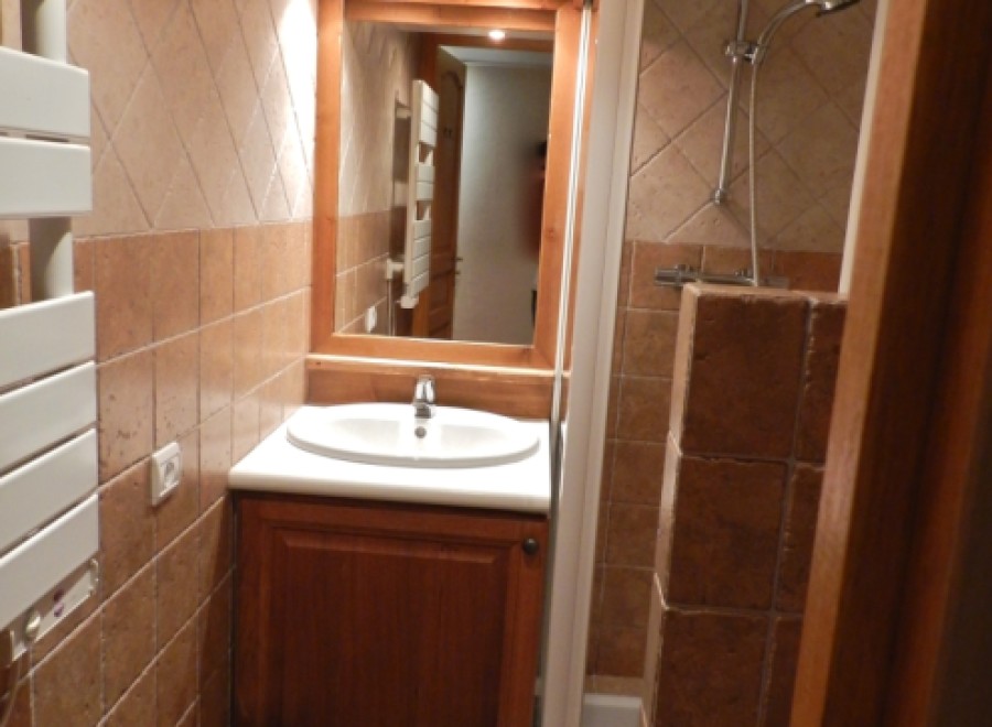 Cozy bathroom with wooden vanity and tiled walls.