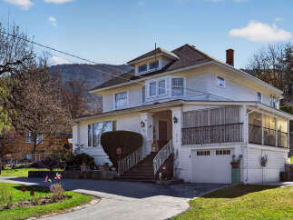 Charming two-story home with a classic design, featuring a welcoming front porch and a well-maintained exterior.