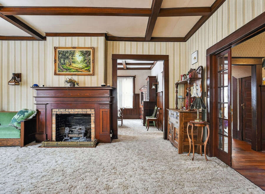 Step back in time with this charming property featuring a cozy living room with a fireplace and plush carpet.