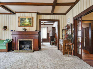 Step back in time with this charming property featuring a cozy living room with a fireplace and plush carpet.