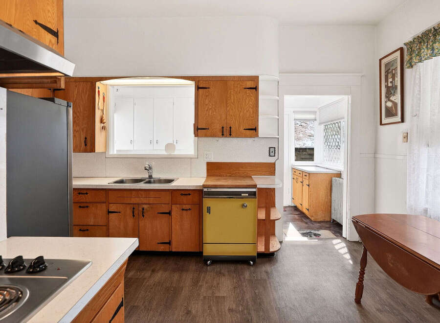 Step into this charming kitchen, featuring classic wooden cabinetry and a unique yellow dishwasher.