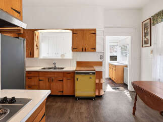 Step into this charming kitchen, featuring classic wooden cabinetry and a unique yellow dishwasher.