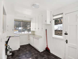 This bright and airy kitchen space offers ample storage with its white cabinetry and countertop.