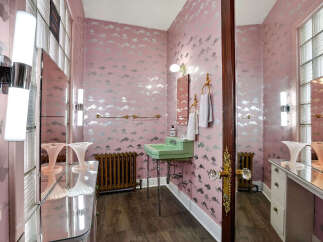 Step into a whimsical bathroom retreat! This space features a unique cloud-patterned wallpaper, a vintage green sink, and elegant fixtures.
