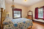 Step into this charming bedroom, featuring a vintage brass bed frame and a cozy, patterned quilt.