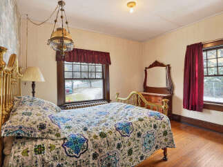 Step into this charming bedroom, featuring a vintage brass bed frame and a cozy, patterned quilt.