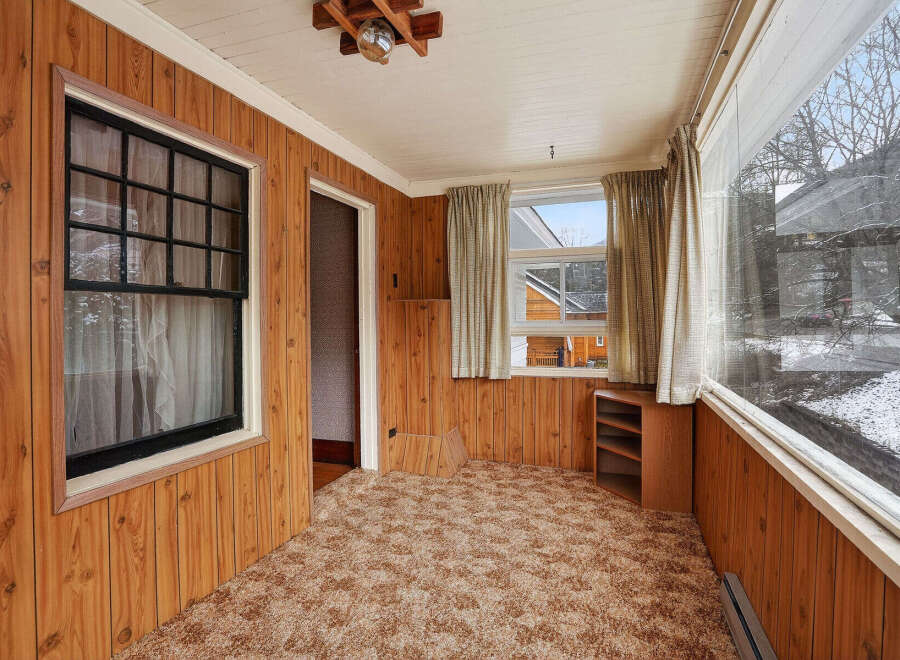 Step into this inviting space with warm wood paneling and a cozy carpet.