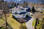 This stunning white house boasts a classic design with a charming porch and a well-maintained lawn.