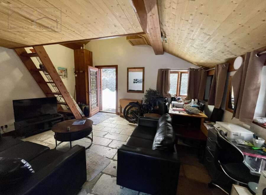 Discover this charming property featuring a cozy living space with a unique wooden ceiling and stone flooring.