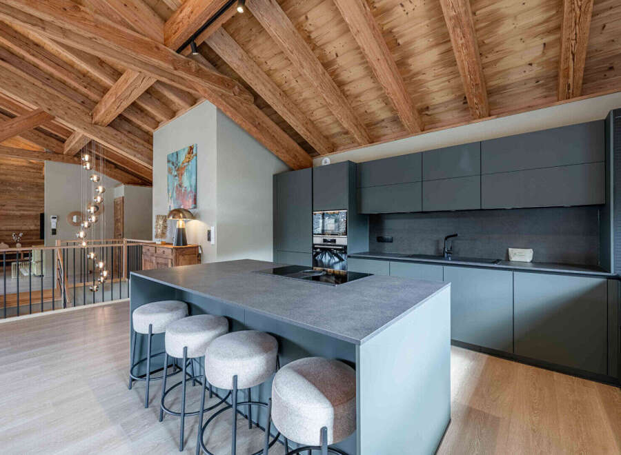 This stunning kitchen boasts a modern design with a rustic touch, featuring exposed wooden beams and sleek, dark cabinetry.