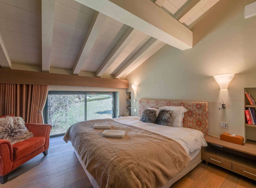 Experience luxury in this stunning bedroom featuring a vaulted ceiling with exposed beams.