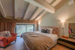 Experience luxury in this stunning bedroom featuring a vaulted ceiling with exposed beams.
