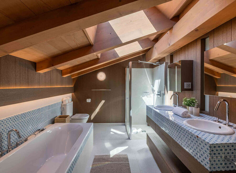 This luxurious bathroom boasts a stunning design with a vaulted wooden ceiling and a skylight that floods the space with natural light.