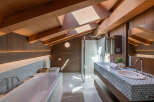 This luxurious bathroom boasts a stunning design with a vaulted wooden ceiling and a skylight that floods the space with natural light.