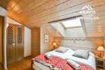 Discover the charm of this cozy bedroom featuring a unique wooden ceiling and walls, creating a warm and inviting atmosphere.