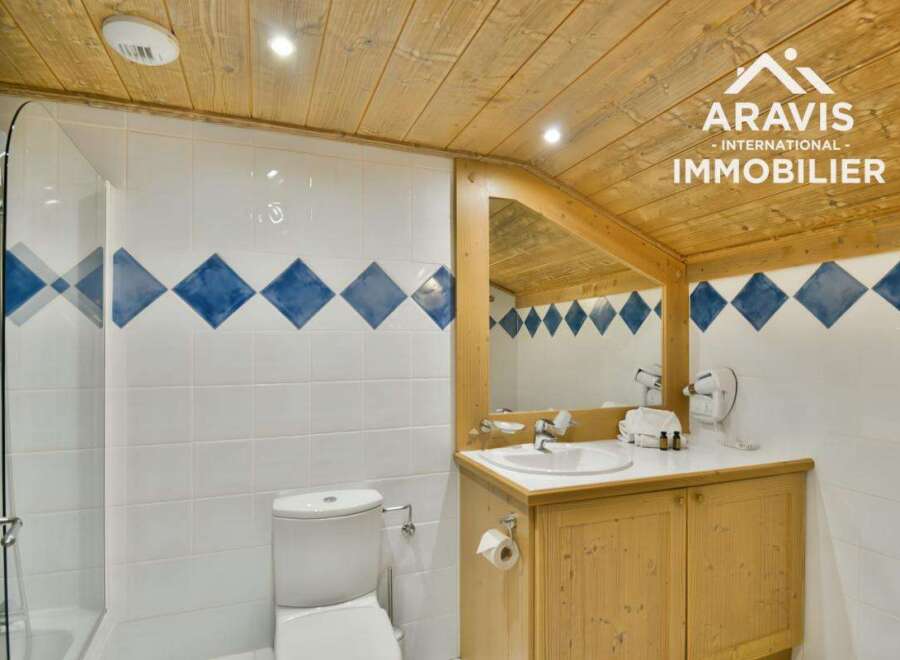 Discover this charming bathroom featuring a unique design with wooden accents and a stylish tiled wall.
