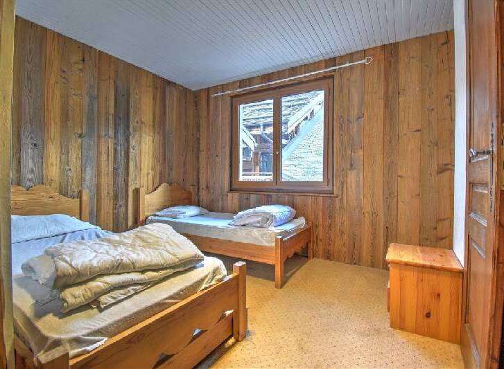 This charming bedroom features rustic wooden walls and two cozy beds, perfect for a relaxing getaway.