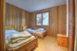 This charming bedroom features rustic wooden walls and two cozy beds, perfect for a relaxing getaway.