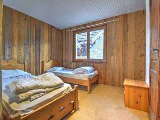 This charming bedroom features rustic wooden walls and two cozy beds, perfect for a relaxing getaway.