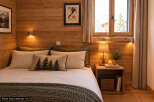Experience cozy mountain living in this charming bedroom, featuring warm wood paneling and a comfortable bed adorned with plush pillows.