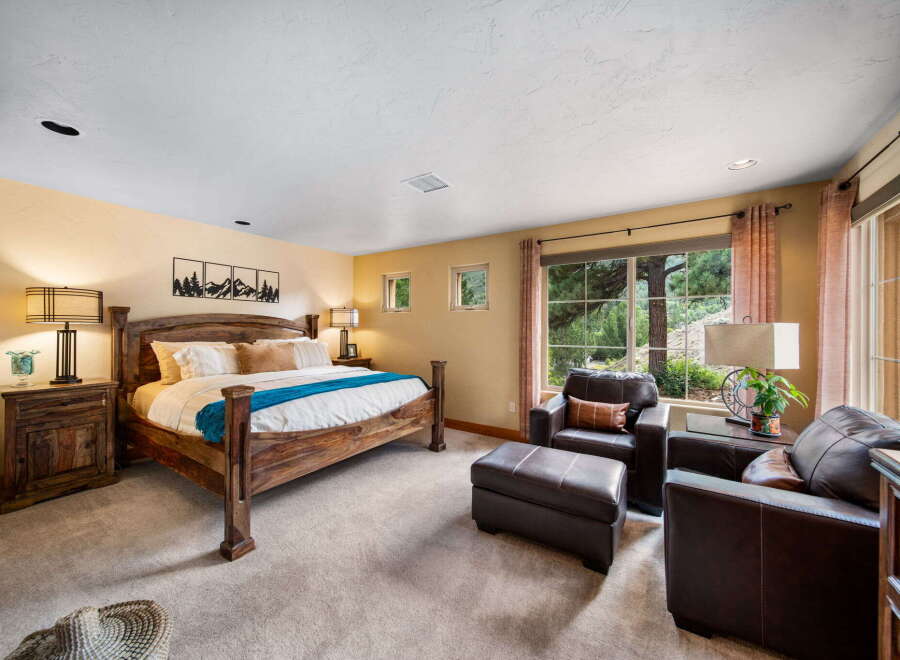 Step into luxury with this stunning bedroom featuring a rustic wooden bed frame and plush seating area.