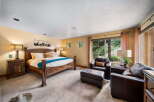 Step into luxury with this stunning bedroom featuring a rustic wooden bed frame and plush seating area.