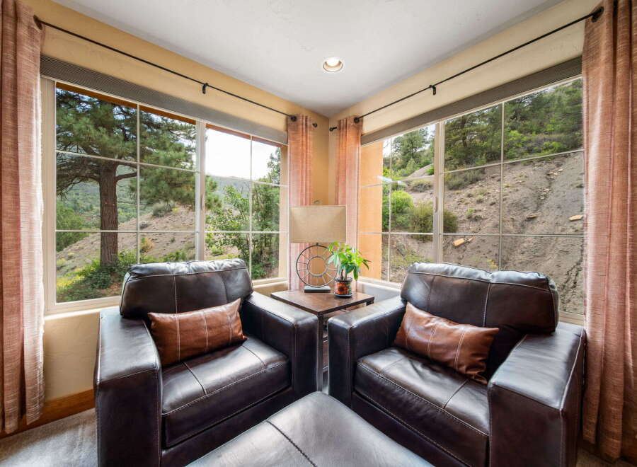 Enjoy breathtaking views from this cozy living space, featuring two comfortable leather armchairs and a stylish ottoman.