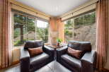 Enjoy breathtaking views from this cozy living space, featuring two comfortable leather armchairs and a stylish ottoman.