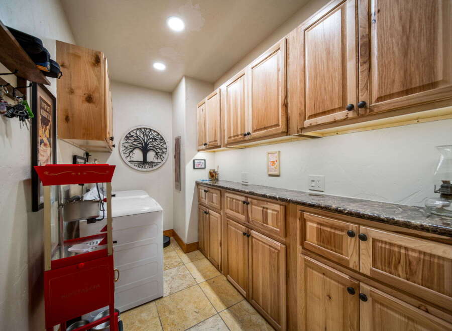 Step into this beautifully designed laundry room, featuring custom wooden cabinetry that offers ample storage space.