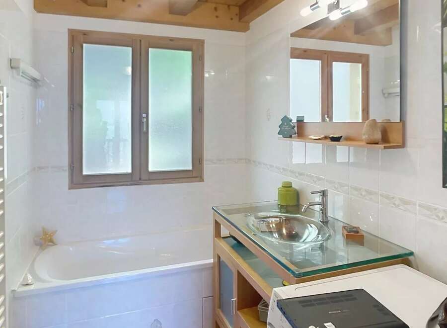 Discover this charming bathroom featuring a unique wooden ceiling and a stylish glass countertop.