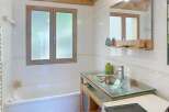 Discover this charming bathroom featuring a unique wooden ceiling and a stylish glass countertop.