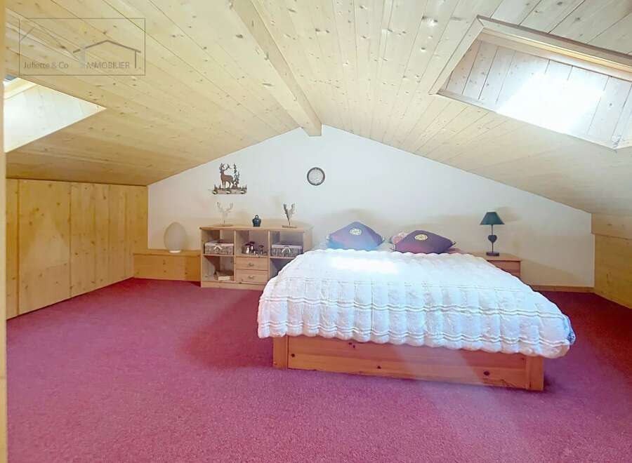 Discover the charm of this cozy bedroom, featuring a unique sloped ceiling and a warm, inviting atmosphere.