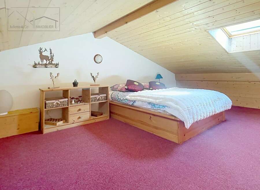 Discover this charming bedroom featuring a cozy wooden bed frame and a plush, inviting carpet.