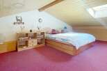 Discover this charming bedroom featuring a cozy wooden bed frame and a plush, inviting carpet.
