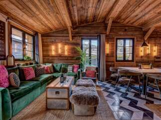 Step into luxury with this stunning property, showcasing a cozy living room with a plush green velvet sofa and a unique wooden ceiling.