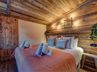 Experience rustic charm in this cozy bedroom, featuring a stunning wooden ceiling and accent wall.