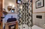 This modern bathroom boasts a stylish design with a geometric tiled shower and a sleek black sink.