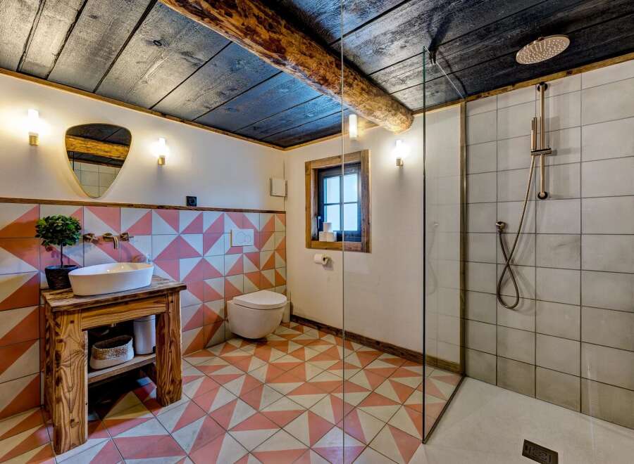 Step into this charming bathroom, featuring a rustic wooden vanity and a unique geometric tile design.