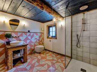 Step into this charming bathroom, featuring a rustic wooden vanity and a unique geometric tile design.