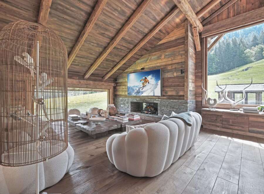 Experience luxury living in this stunning chalet, featuring a cozy living room with a fireplace and a large TV.