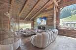 Experience luxury living in this stunning chalet, featuring a cozy living room with a fireplace and a large TV.